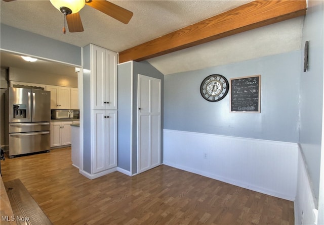 kitchen with white cabinets, vaulted ceiling with beams, dark hardwood / wood-style floors, and stainless steel fridge