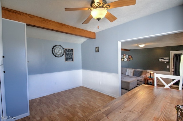 unfurnished living room with beam ceiling, ceiling fan, and hardwood / wood-style flooring