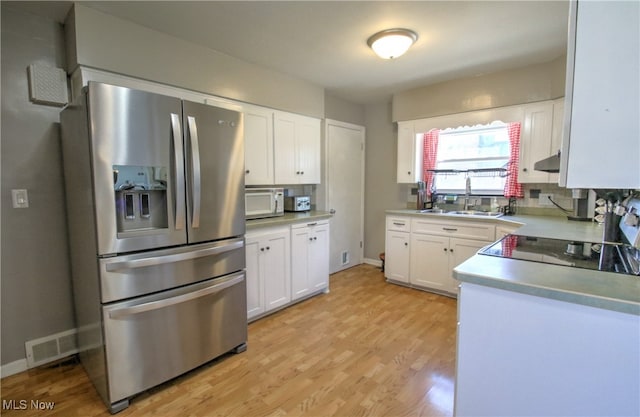 kitchen with sink, light hardwood / wood-style floors, stainless steel fridge with ice dispenser, and white cabinetry