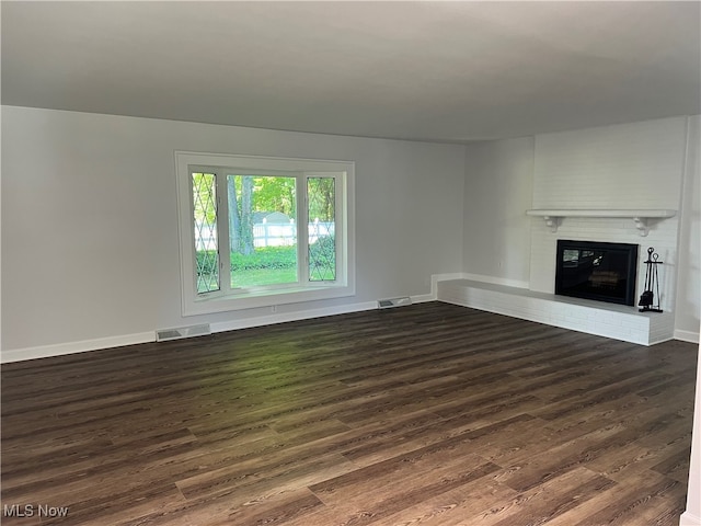 unfurnished living room featuring dark wood-type flooring and a fireplace