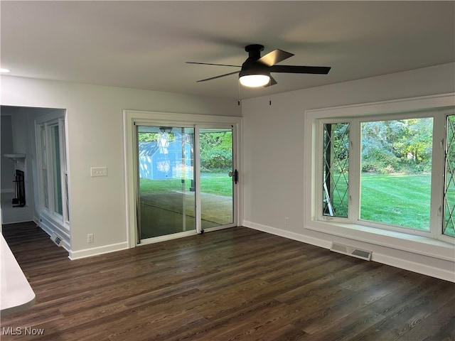 empty room with ceiling fan, dark hardwood / wood-style flooring, and plenty of natural light