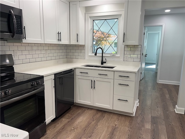 kitchen with dark hardwood / wood-style flooring, black appliances, sink, and white cabinets