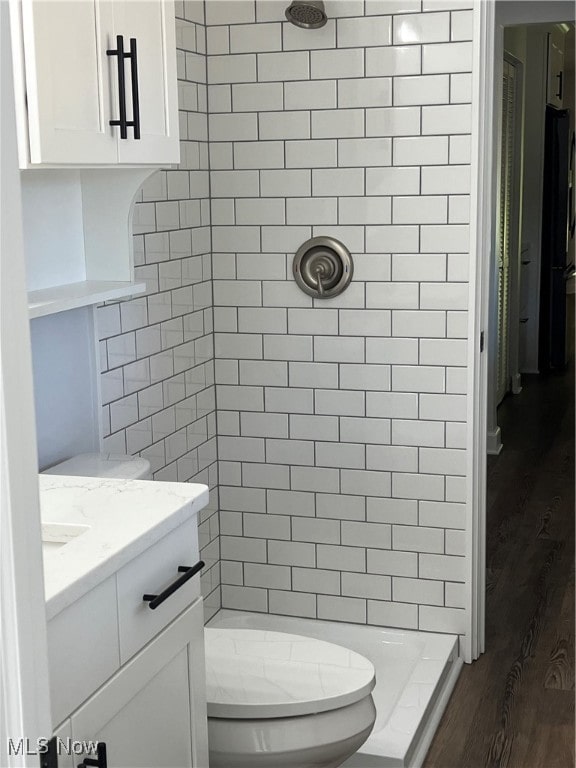 bathroom featuring vanity, toilet, hardwood / wood-style flooring, and tiled shower