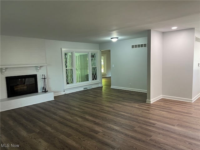 unfurnished living room featuring dark wood-type flooring and a fireplace