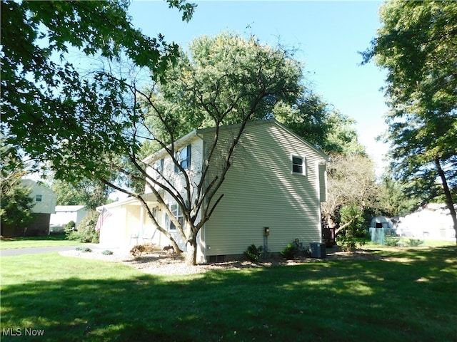 view of side of property featuring a lawn and central AC