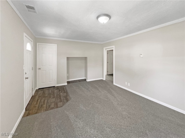 unfurnished room with dark carpet, a textured ceiling, and ornamental molding