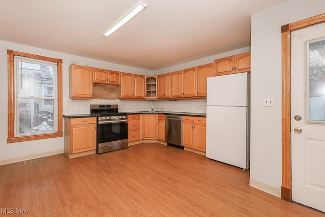 kitchen featuring stainless steel appliances, light wood-type flooring, and tasteful backsplash