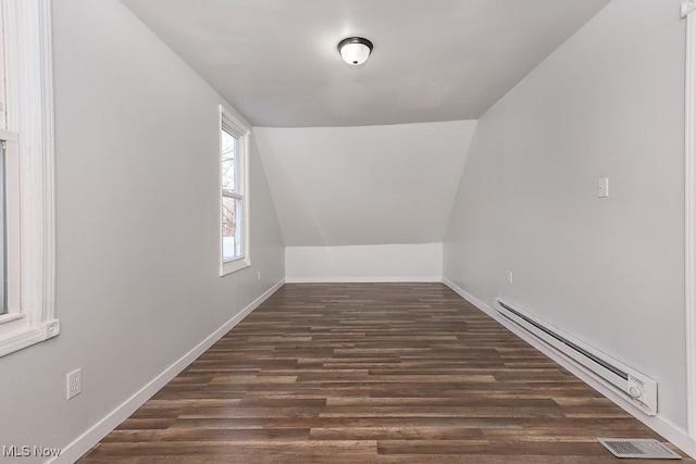 additional living space featuring lofted ceiling, dark hardwood / wood-style flooring, and a baseboard heating unit