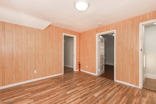 unfurnished bedroom featuring wood-type flooring, wood walls, and a closet