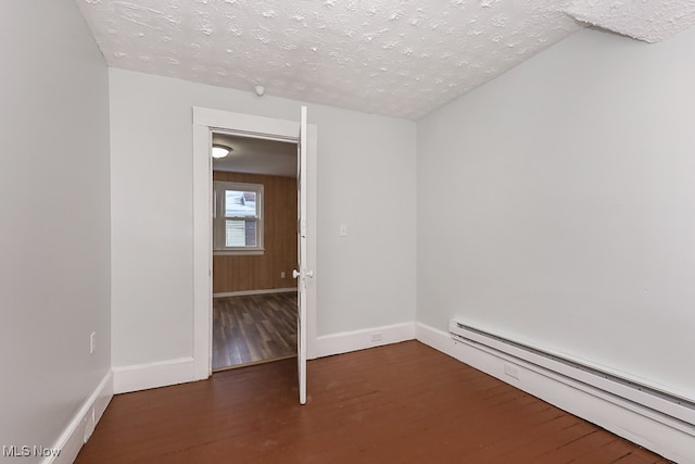 unfurnished room with a baseboard radiator, a textured ceiling, and dark wood-type flooring