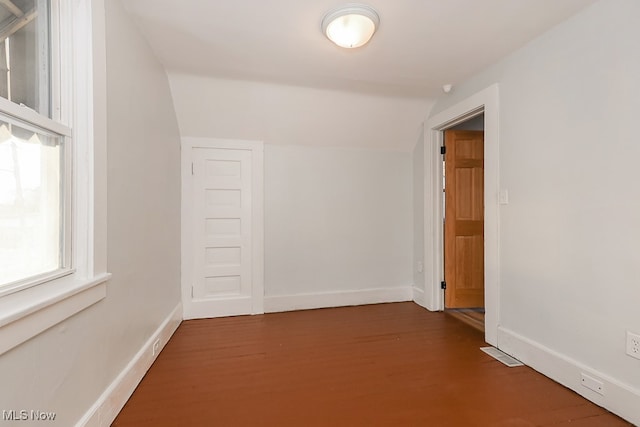 corridor with wood-type flooring and vaulted ceiling