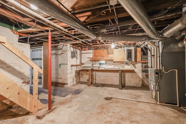 basement featuring electric panel and heating unit