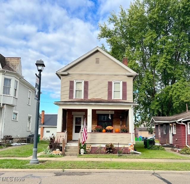 front facade with covered porch and a front yard