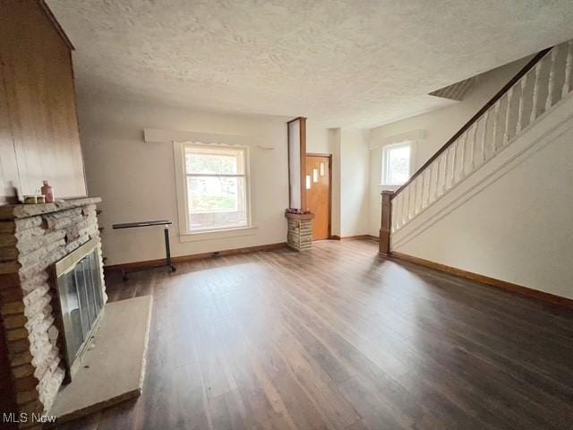 unfurnished living room featuring a textured ceiling, dark hardwood / wood-style floors, and a fireplace