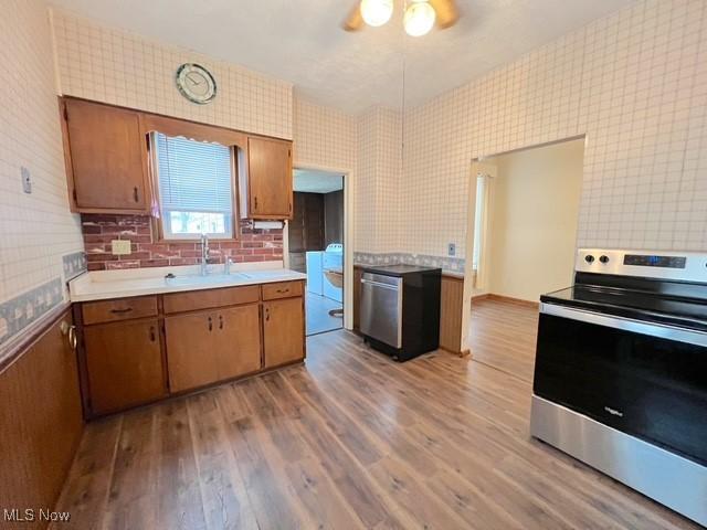 kitchen with stainless steel range, light wood-type flooring, ceiling fan, and sink