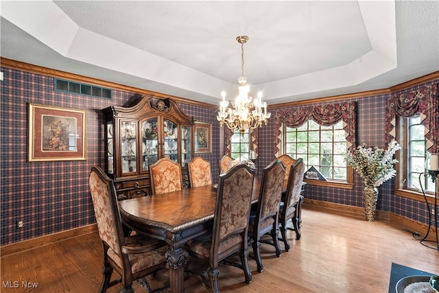 dining area with wood-type flooring, an inviting chandelier, and a healthy amount of sunlight