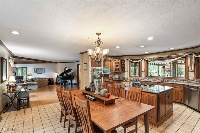 dining space featuring ornamental molding, light tile patterned flooring, a chandelier, and a textured ceiling