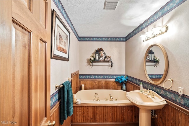 bathroom featuring a textured ceiling and a bath