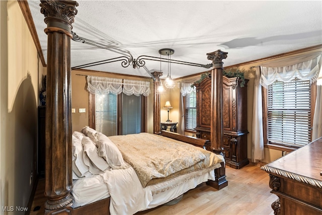 bedroom with a textured ceiling, crown molding, and light hardwood / wood-style flooring