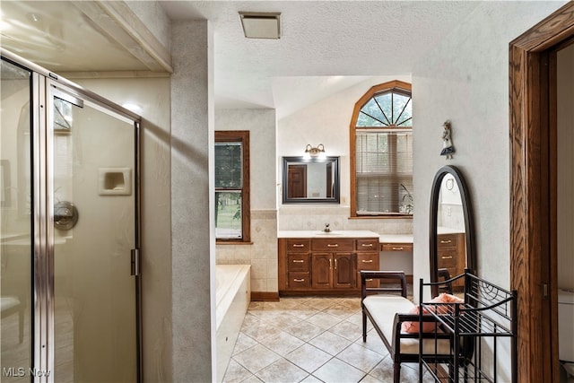 bathroom with vanity, a textured ceiling, lofted ceiling, tile patterned flooring, and shower with separate bathtub