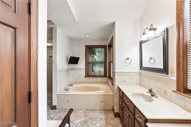 bathroom with a textured ceiling, vanity, a washtub, and tile patterned floors