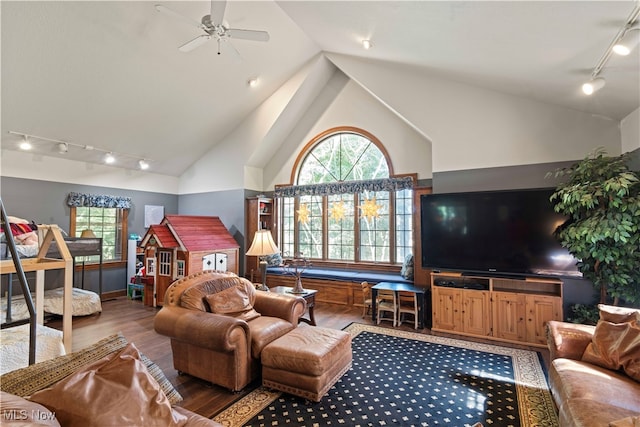 living room featuring rail lighting, ceiling fan, wood-type flooring, and high vaulted ceiling