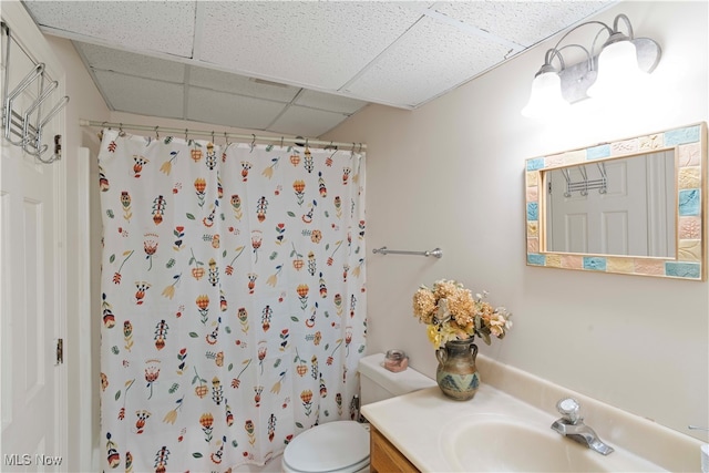 bathroom with a drop ceiling, a shower with shower curtain, vanity, and toilet