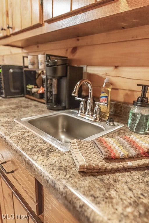 kitchen with light brown cabinets, wood walls, and sink