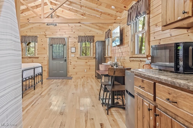 kitchen featuring lofted ceiling with beams, wood walls, and a healthy amount of sunlight