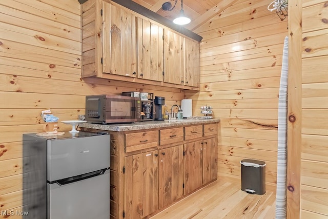 kitchen featuring appliances with stainless steel finishes, light wood-type flooring, and wood walls