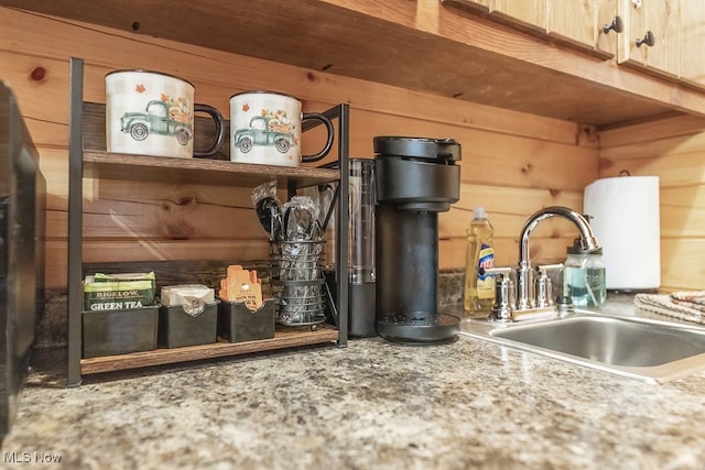 details featuring wooden walls, light brown cabinetry, and sink