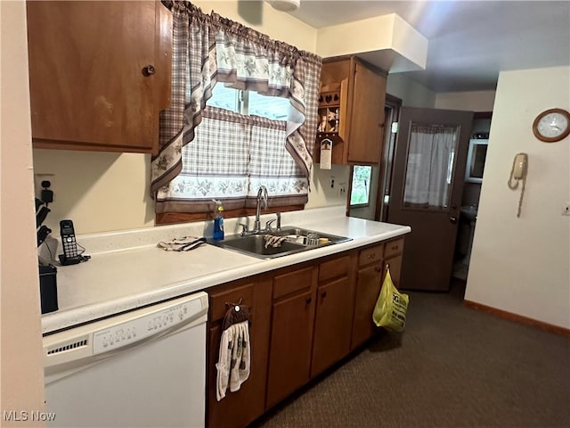 kitchen featuring dark colored carpet, white dishwasher, and sink