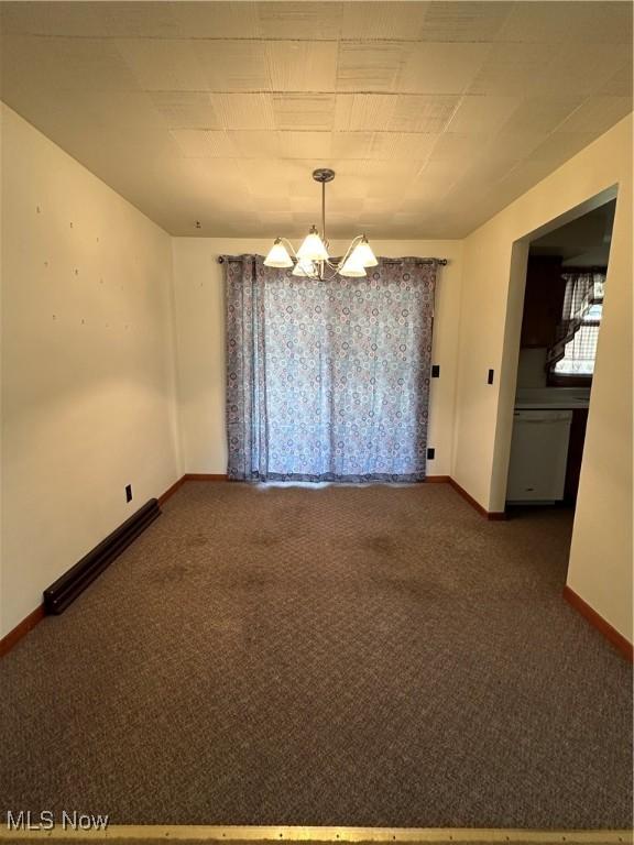 carpeted empty room featuring a notable chandelier