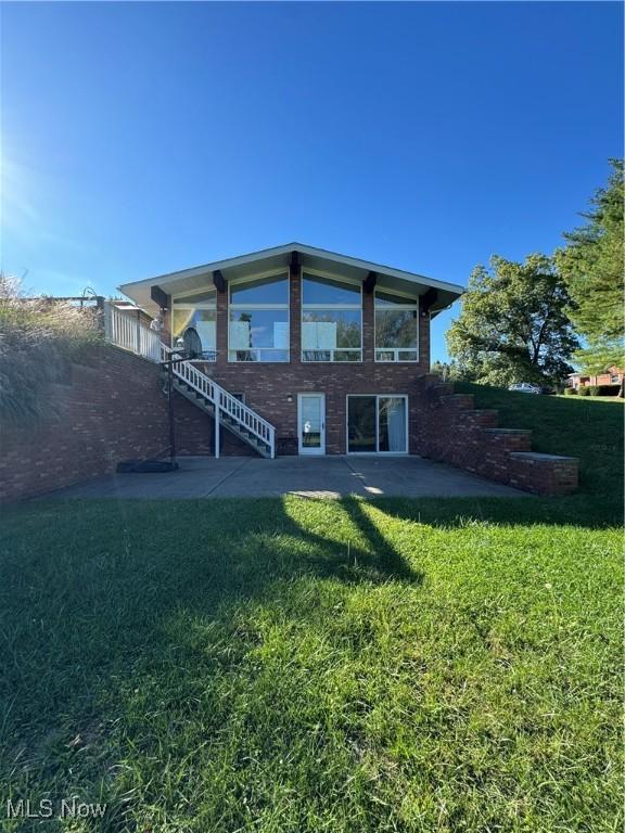 rear view of house featuring a patio area, stairway, and a lawn