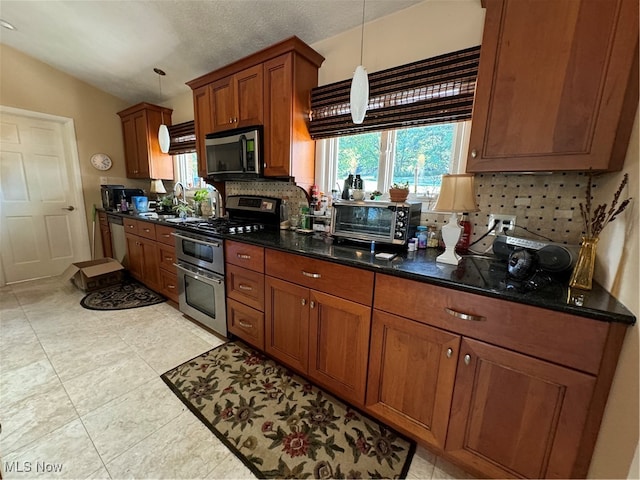 kitchen featuring a toaster, appliances with stainless steel finishes, decorative backsplash, brown cabinetry, and decorative light fixtures