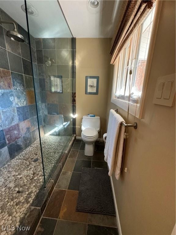 bathroom featuring toilet, baseboards, and a walk in shower