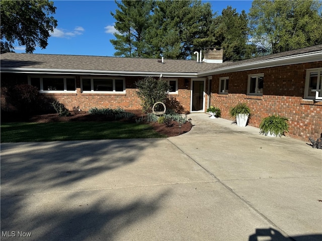 view of front of home featuring a chimney and brick siding