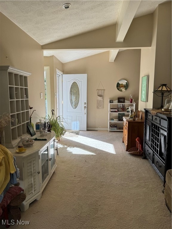 entrance foyer with a textured ceiling, light carpet, and vaulted ceiling with beams