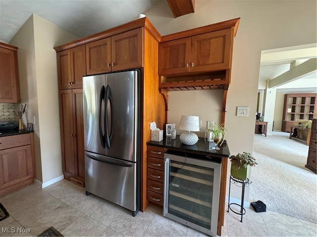 kitchen with light carpet, dark countertops, wine cooler, brown cabinets, and freestanding refrigerator