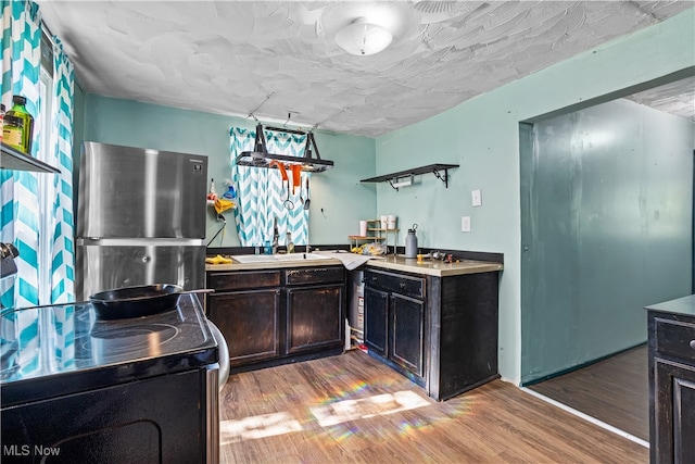 kitchen with light wood-type flooring, sink, range with electric cooktop, and stainless steel refrigerator