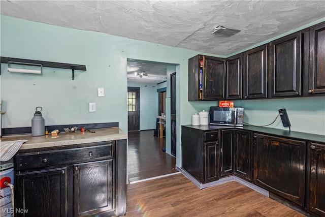 kitchen with wood-type flooring, a textured ceiling, and dark brown cabinetry