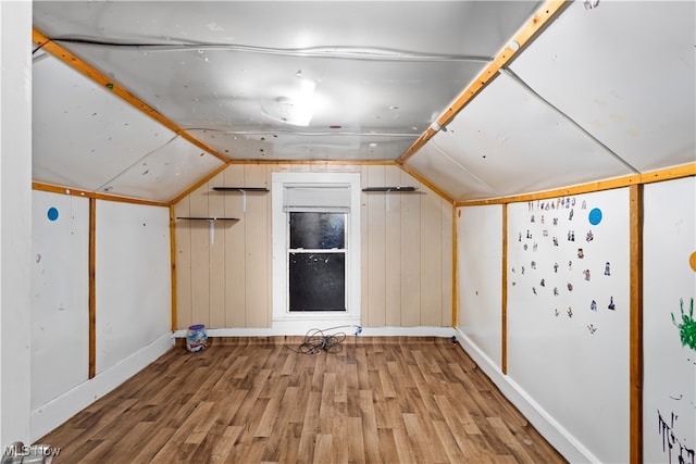 additional living space featuring wood walls, vaulted ceiling, and hardwood / wood-style flooring