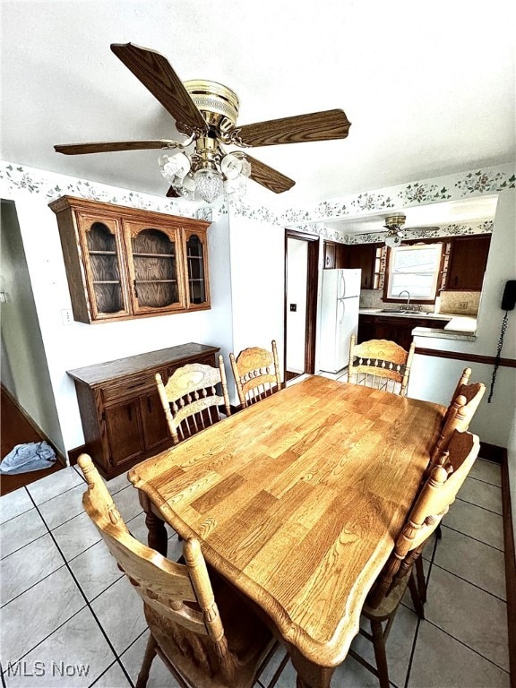 tiled dining area featuring ceiling fan and sink