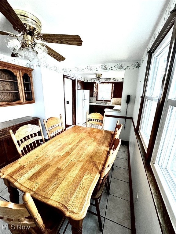 tiled dining area featuring ceiling fan and sink