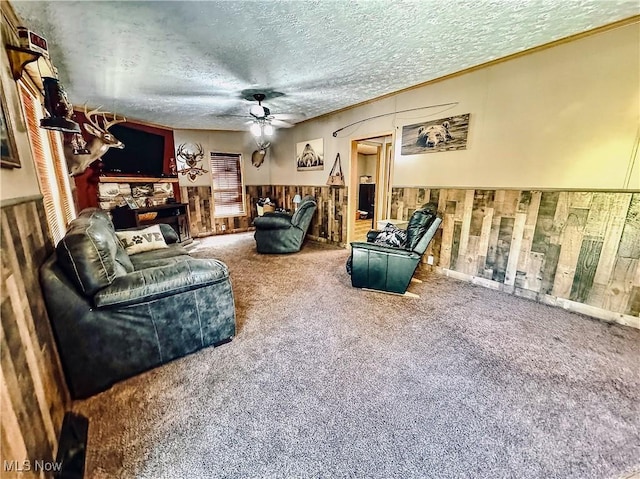 living room with carpet, a textured ceiling, ceiling fan, and wooden walls