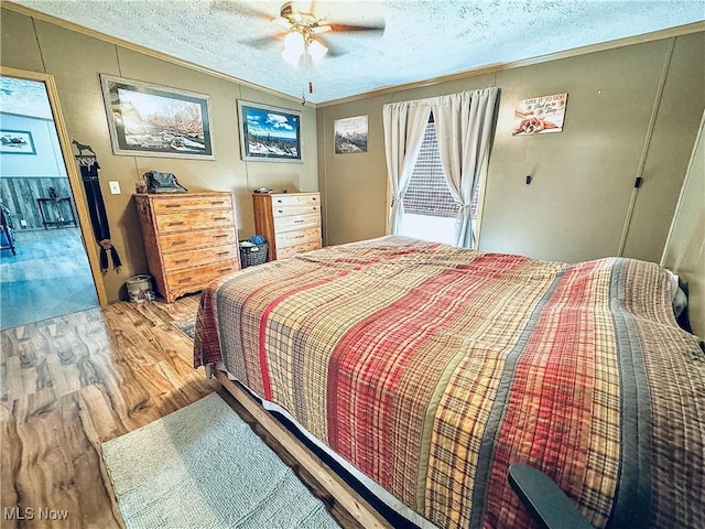 bedroom featuring ceiling fan, crown molding, wood-type flooring, and a textured ceiling