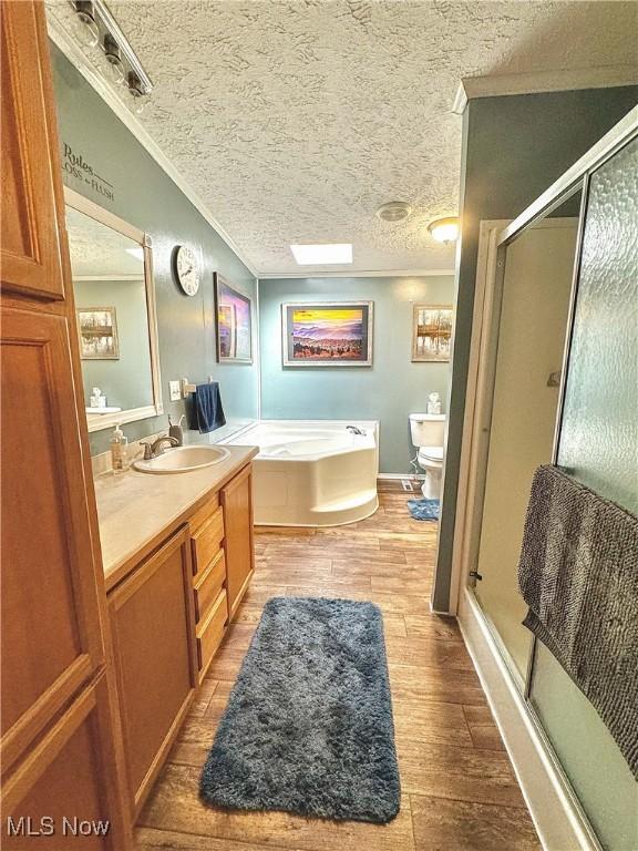 full bathroom with separate shower and tub, crown molding, wood-type flooring, and a textured ceiling