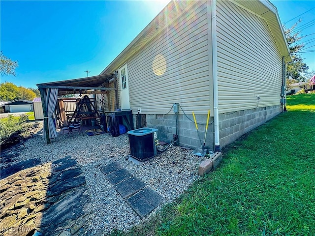 view of side of home with central air condition unit and a lawn