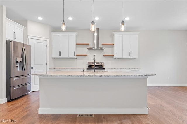 kitchen featuring stainless steel appliances, a kitchen island with sink, wall chimney range hood, pendant lighting, and white cabinetry