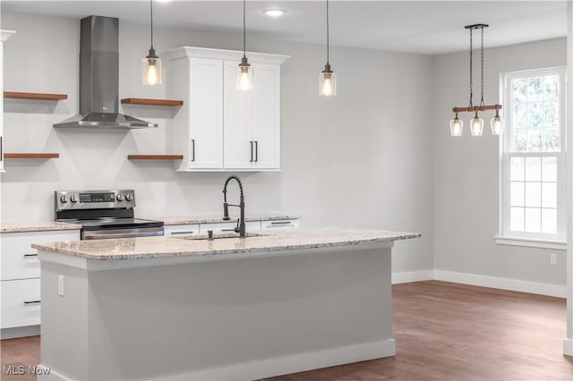 kitchen featuring stainless steel electric stove, sink, wall chimney range hood, white cabinetry, and an island with sink